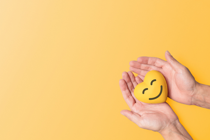 Hands tenderly holding a yellow resin heart against a matching yellow background, symbolizing mental health awareness and the significance of September Yellow, a month dedicated to mental well-being and suicide prevention